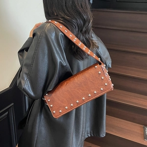 Retro brown faux leather underarm bag with silver studs worn with a black leather jacket