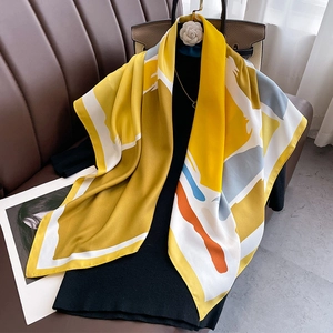 Elegant yellow silk scarf with geometric print on a hanger in a fashion setting