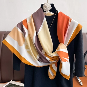 Elegant geometric color-block silk scarf in orange and yellow on a chic black sweater