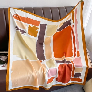 Detailed macro view of abstract silk square scarf with orange and brown geometric brushstrokes