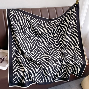 Close-up of zebra pattern silk square scarf draped on a brown leather surface