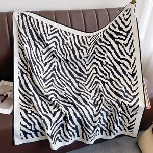 Classic black and white zebra pattern square scarf displayed on a leather background