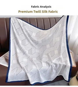 Detail of high-quality twill silk square scarf with blue geometric lines on leather sofa