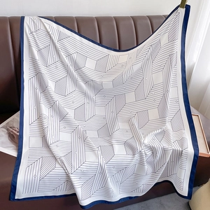 Close-up of geometric pattern silk scarf with satin finish on leather sofa