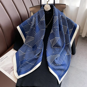 Navy silk scarf with white geometric lines and border draped on a black outfit
