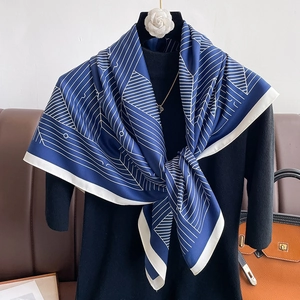 Close-up of luxury navy satin scarf with white geometric linear pattern and fine stitching