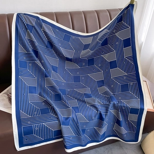 Detail of navy blue silk scarf with white geometric patterns on a leather background