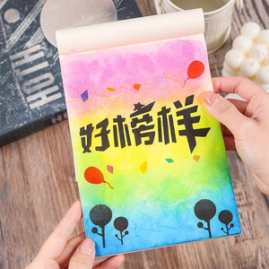 Rainbow gradient stationery notebook with Good Exemplar art text on a wooden desk
