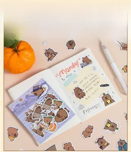 Close-up of 40-piece capybara sticker set scattered on notebook with cozy stationery vibes