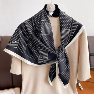 Detail of elegant black and white geometric print silk scarf tied on a chic outfit
