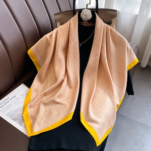 Close-up of geometric pattern silk scarf with peach and lemon yellow contrast edges