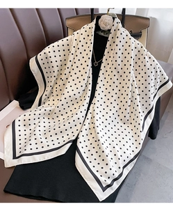 Detailed view of white polka dot silk scarf with black borders and smooth texture