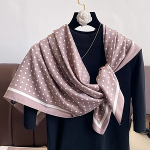 Detail of dusty rose polka dot silk scarf tied on a black mannequin with satin texture