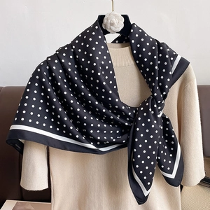 Close-up of black and white polka dot silk scarf styled on a beige turtleneck sweater