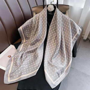 Close-up of silk scarf with white polka dots on grey fabric and smooth texture