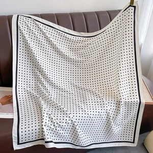 Polka dot silk scarf draped over a leather sofa showing draped texture and pattern