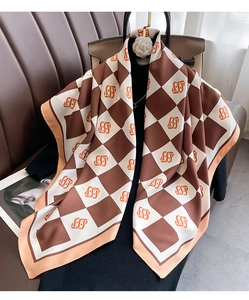 Close-up of checkerboard silk scarf with orange letter motifs and pink borders