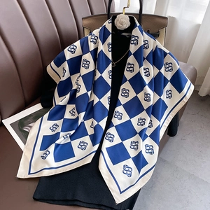 Detailed view of dark blue checkered silk scarf with letter print on a mannequin