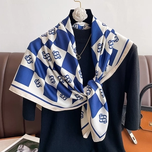 Elegant blue and white checkered silk scarf with luxury monogram on a dark background