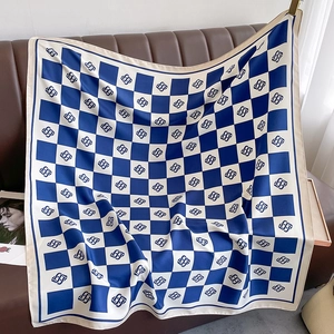 Detail of navy blue and white checkerboard silk scarf draped on a leather sofa