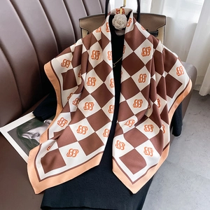 Close-up of a large plaid silk scarf with orange patterns on a black designer handbag
