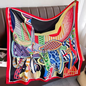 Elegant 90x90cm geometric silk scarf with bold abstract patterns on a leather sofa