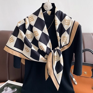 Detail of silk-feel scarf with black and white checkerboard pattern and gold monogram