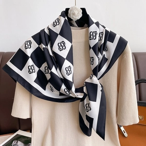 Detail of checkered silk scarf with SS monogram pattern tied on beige knit top