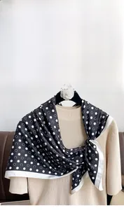 Close-up of black and white polka dot silk scarf draped over a beige sweater
