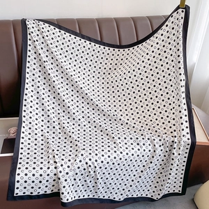 Detailed view of silk scarf with polka dots and C pattern on a leather background