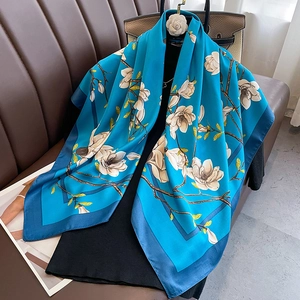 Detailed close-up of blue silk scarf featuring elegant white magnolia floral patterns