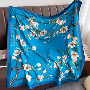 Detailed close-up of blue floral silk shawl with white magnolia pattern on leather