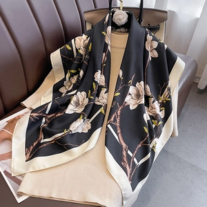 Elegant black silk floral scarf with white magnolia print on beige knit background