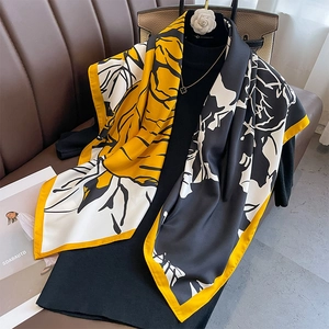 Floral print silk scarf with black and yellow patterns used as a stylish shawl wrap