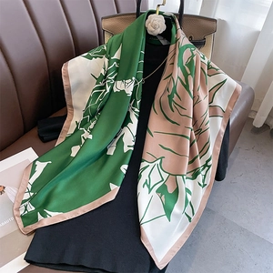 Detailed view of floral silk scarf featuring rich green and cream botanical prints