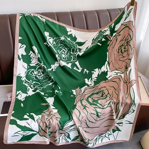 Close-up of floral emerald green silk scarf featuring pink rose prints on leather texture