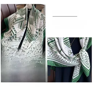 Détail d'un foulard en soie verte à motif paisley attaché à un sac à main classique