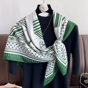 Détail d'un foulard en soie noué sur un pull avec motifs cachemire vert émeraude