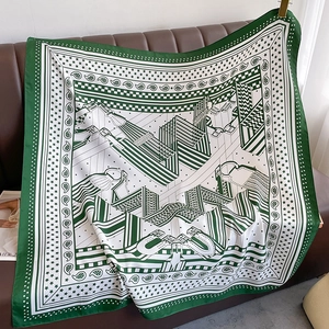Détail d'un carré de soie avec motif équestre vert forêt sur un canapé en cuir