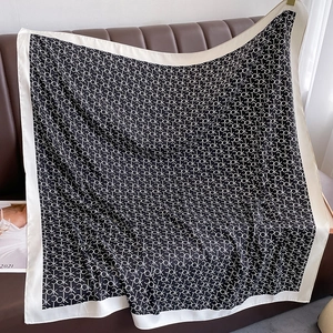 Détail d'un grand foulard carré en soie avec motif de lettres sur canapé en cuir brun