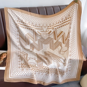 Détail du motif équestre de luxe sur un foulard carré en soie drapé sur du cuir marron