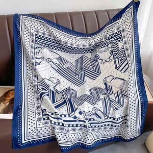 Détail d'un foulard en soie bleu et blanc à motifs équestres sur un canapé brun
