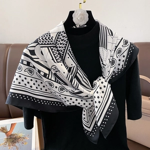 Détail du foulard en soie aux motifs géométriques noirs et blancs et motif paisley