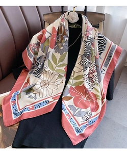 Detail of floral and zebra print silk scarf draped over a black dress with luxury bag