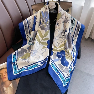 Close-up of floral silk scarf with dark blue border and elegant flower patterns
