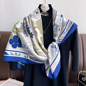 Elegant floral silk scarf with blue and green flower patterns on a fashion mannequin