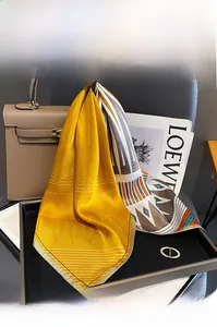 Detailed texture of yellow mulberry silk small square scarf tied on a leather handbag