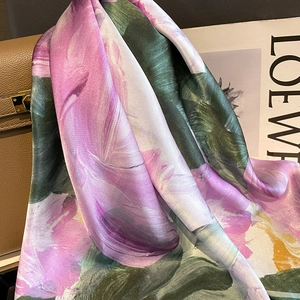 Elegant silk scarf with purple floral patterns draped over a stylish leather handbag