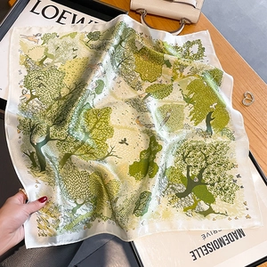 Silk square scarf with green forest deer print on an elegant wooden tabletop setting