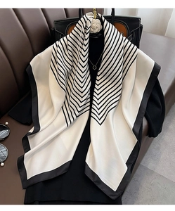 Detail of elegant black and white chevron silk scarf styled with premium accessories